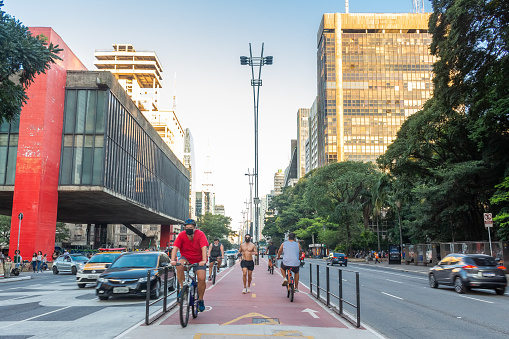 Car movements and people practicing physical activities, walking and cycling on Avenida Paulista, a tourist destination in the city of São Paulo with a view of the city's arts museum (MASP).