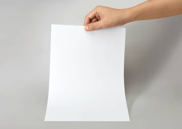 istock Hand holding a blank a4 size paper isolated on grey background. 1313037376