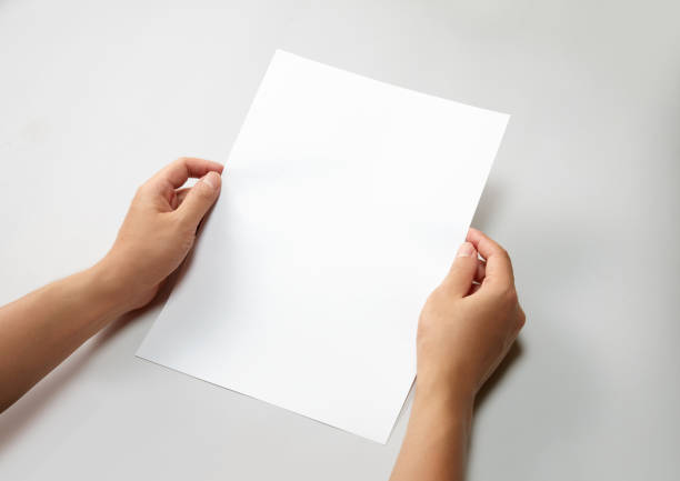 istock Hand holding a blank a4 size paper isolated on grey background. 1313037805
