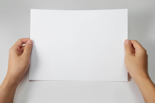 istock Hand holding a blank a4 size paper isolated on grey background. 1313037806