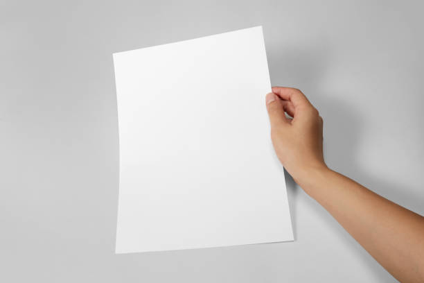 istock Hand holding a blank a4 size paper isolated on grey background. 1313037808