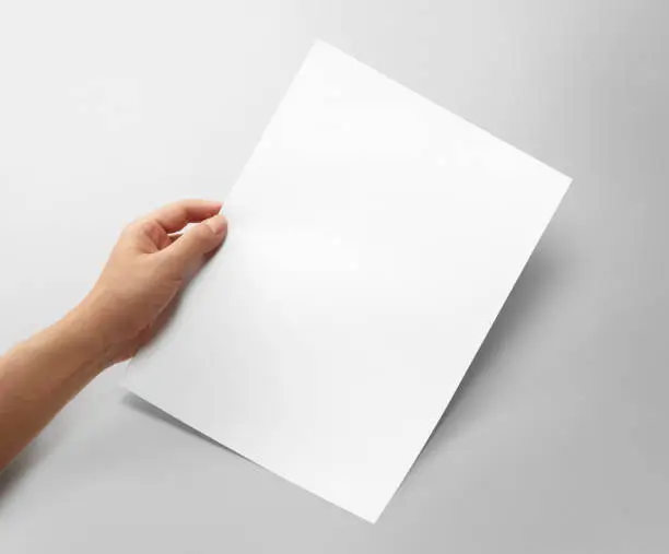 Photo of Hand holding a blank a4 size paper isolated on grey background.