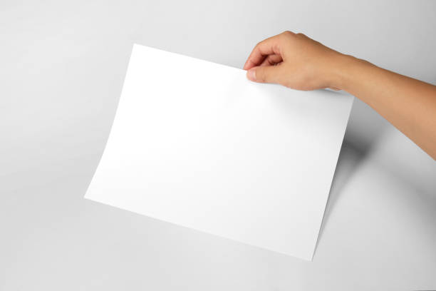 istock Hand holding a blank a4 size paper isolated on grey background. 1313037811