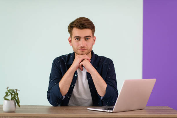 Smiling young man freelancer using laptop studying online working from home, happy casual millennial guy typing on pc notebook surfing internet .