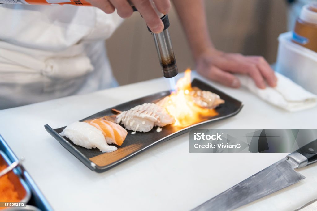 The Chef Is Grilling Sashimi Sushi With Spray Gun Stock Photo