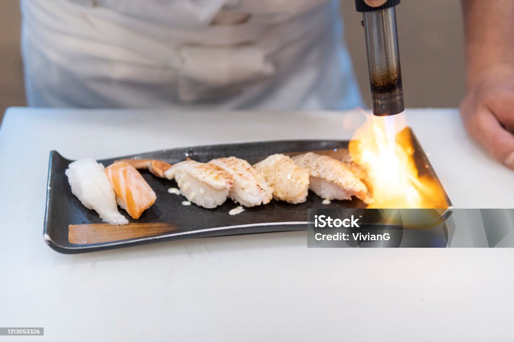 The Chef Is Grilling Sashimi Sushi With Spray Gun Stock Photo