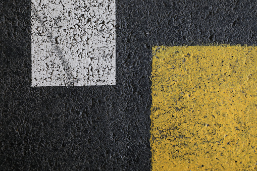 Yellow and white lines on the dark gray asphalt. \nRoad with painted traffic lines, \nhorizontal format for a  background concept.