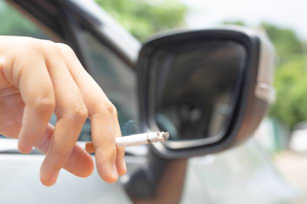 Woman driving a car smokes, focus on cigarettes stock photo