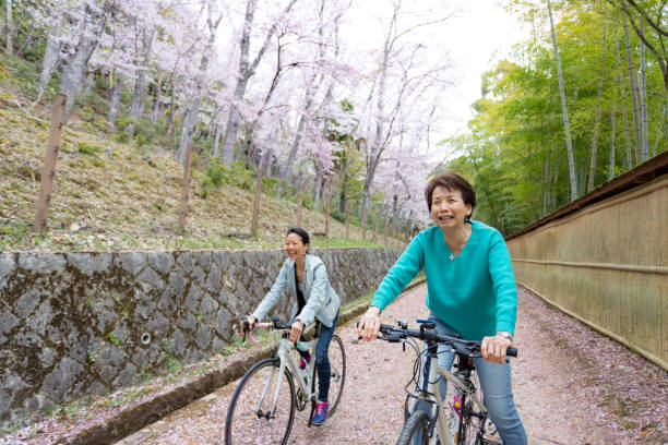 Mother and daughter enjoy cycling through cherry blossoms