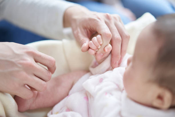 Asian baby holding dad's finger