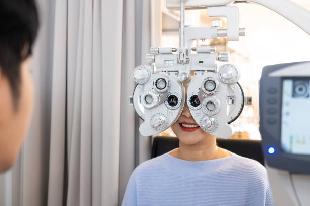 selektywne ustawianie ostrości w sprzęcie ramy optometry. podczas gdy lekarz za pomocą penlight i subiektywne załamanie do zbadania systemu wzrokowego oczu starszych pacjentek z profesjonalną maszyną przed wykonane okulary. - penlight zdjęcia i obrazy z banku zdjęć