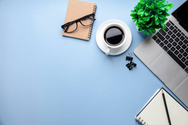 istock Flat lay, top view office table desk. Workspace with, laptop,office supplies, pencil, green leaf, and coffee cup on blue background. 1313069874