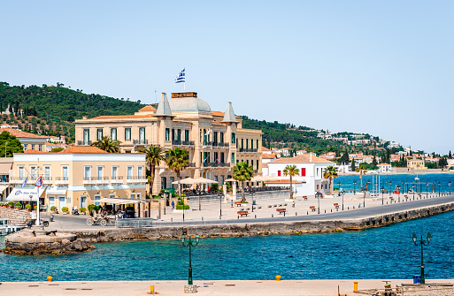Spetses, Greece - April 28 2018: View of the port and the waterfront. The Poseidonion Grand Hotel, one of the most luxurious hotels in southeastern Europe is a landmark on the Spetses skyline.