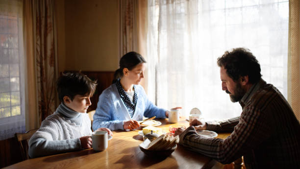 Portrait of poor sad small girl with parents eating indoors at home, poverty concept. A portrait of poor sad small girl with parents eating indoors at home, poverty concept. family mother poverty sadness stock pictures, royalty-free photos & images