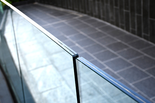 Tempered laminated glass railing balustrade panels frame less ,safety glass for modern architectural buildings. Concept image for exterior path railing and landscape design.