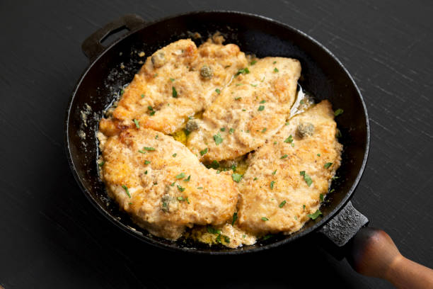istock Homemade Italian Chicken Piccata in a cast iron pan on a black surface, low angle view. 1313080914