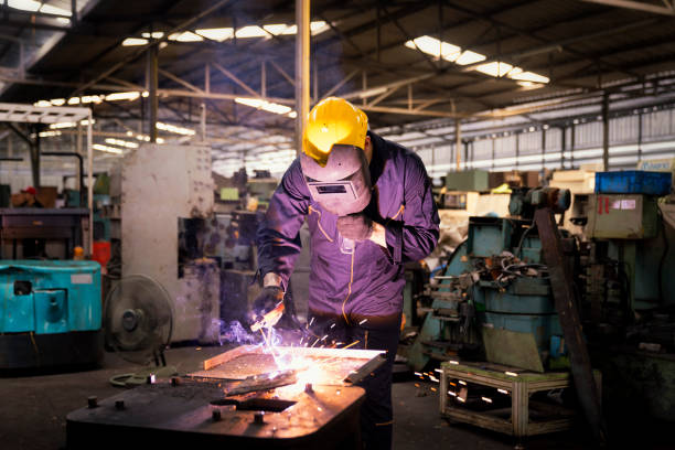 Factory technicians are welding young.  Metal welding steel works using electric arc welding machine to weld steel at factory.