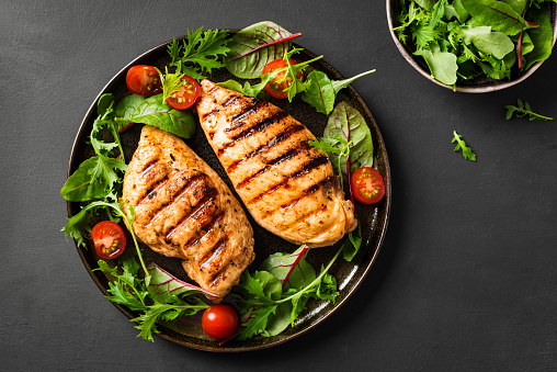 Grilled chicken breast, fillet, steak and fresh vegetable salad, top view, copy space. Healthy keto, ketogenic lunch menu with chicken meat and organic veggies and greens.