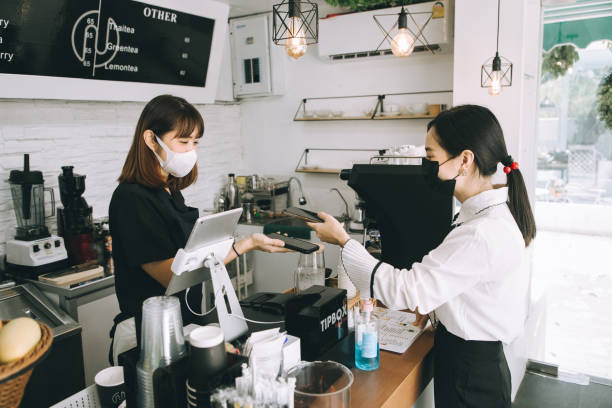 asiatische frau café-besitzerin geschäftsfrau erhalten zahlung von ihrem kunden am schalter mit qr-code kontaktloses bezahlen - stockfoto - café kultur stock-fotos und bilder