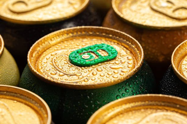 Cold metal beer cans with water drops. Alcoholic drink. Gold-colored lids.
