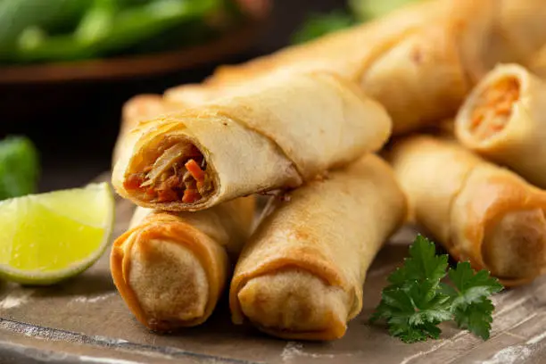 Photo of Fried vegetable spring rolls with sweet chili and soya sauce on wooden board
