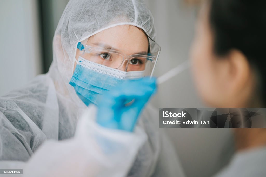 asian chinese female doctor with PPE taking nasal swab from patient Coronavirus test. Medical worker in protective suite taking a swab for corona virus test, potentially infected woman rapid diagnostic test asian chinese female doctor with PPE taking mouth swab from patient Coronavirus test. Medical worker in protective suite taking a swab for corona virus test, potentially infected woman Coronavirus Stock Photo