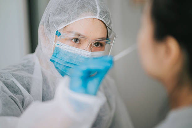 asian chinese female doctor with ppe taking nasal swab from patient coronavirus test. medical worker in protective suite taking a swab for corona virus test, potentially infected woman - pcr device imagens e fotografias de stock