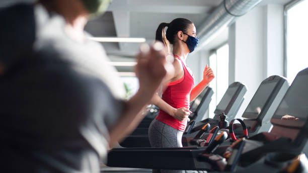 istock Woman with face mask doing exercise on treadmill in gym, coronavirus concept. 1313087703
