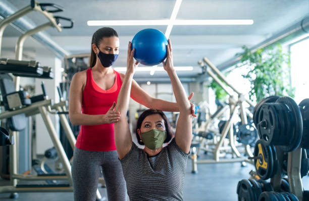 Senior woman with personal trainer doing exercise in gym, coronavirus concept. Active senior woman with personal trainer doing exercise in gym, coronavirus concept. fitness trainer stock pictures, royalty-free photos & images