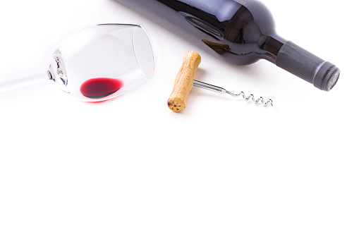 High angle view of a cup of wine, a wine bottle and a wooden handle screw cap laying at the top of the image leaving a useful copy space at the lower side on white background. Studio shot taken with Canon EOS 6D Mark II and Canon EF 100 mm f/ 2.8