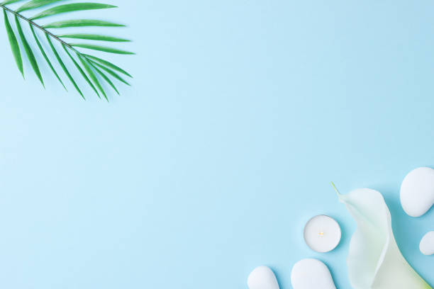 istock Spa background with white stones, candles, palm leaf and white flower on blue. Flat lay,copy space 1313095689