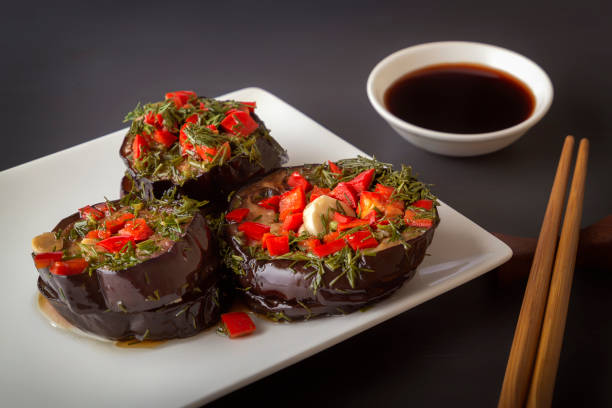 istock Marinated eggplant with red pepper, garlic and herbs in a white plate on a dark table with soy sauce and chopsticks. 1313099958