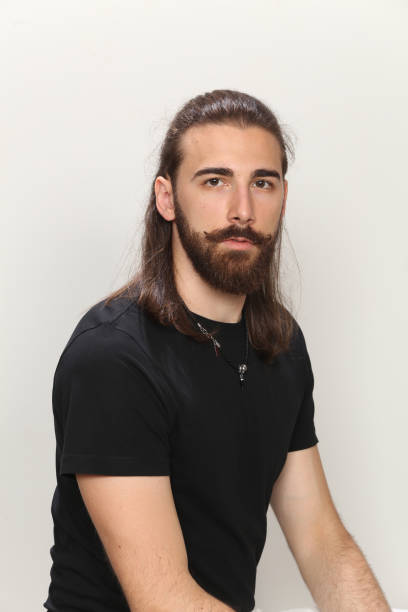 istock Attractive young male model with long hair and beard is posing in studio. 1313105788
