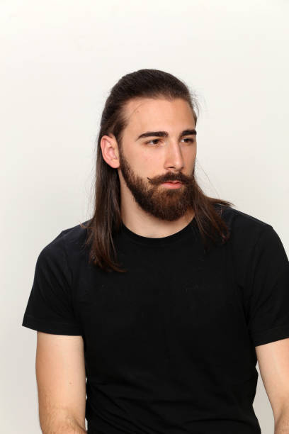 istock Attractive young male model with long hair and beard is posing in studio. 1313105792