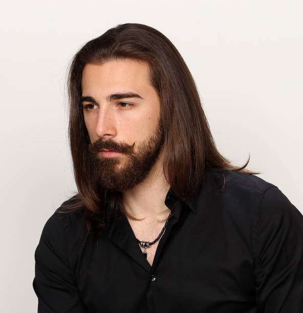 istock Attractive young male model with long hair and beard is posing in studio. 1313106485