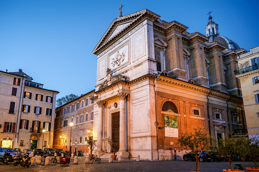 Rome, Italy, April 09 -- An evening view of the church and the square of San Salvatore in Lauro, along Via dei Coronari. This ancient street, frequented by tourists for its typical antique shops and Roman cuisine restaurants, is still an important pedestrian route between the area of St. Peter's Basilica and the Roman Pantheon district. The church of San Salvatore, built in the 16th century in baroque and neoclassical style, is very popular among the faithful for the rites in honor of San Padre Pio of Petralcina. Image in high definition format.