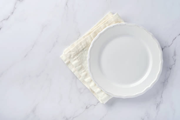istock Empty white plate and towel over white marble table for your recipe or menu. Top view. Mock up. 1313109808
