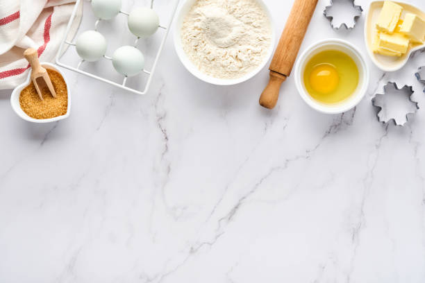 istock Baking background with flour, eggs, kitchen tools, utensils and cookie molds on white marble table. Top view. Flat lay style. Mock up. 1313109918