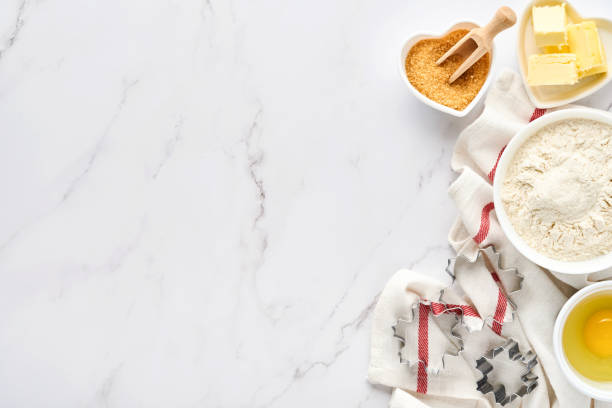 istock Baking background with flour, eggs, kitchen tools, utensils and cookie molds on white marble table. Top view. Flat lay style. Mock up. 1313110306