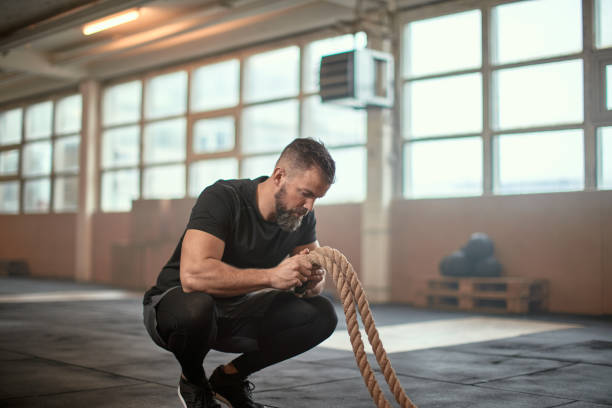 istock Man holding battle ropes on a gym floor 1313111826
