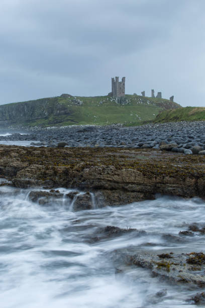 istock Dunstanburgh castle with rocky beach and sea. 1313115209