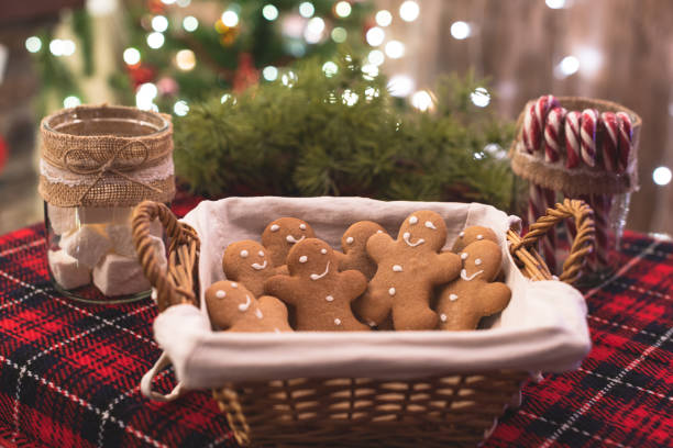 istock Straw basket with gingerbread man, marshmallows, candies on the table on the christmas tree background with beautiful light bokeh. 1313115522