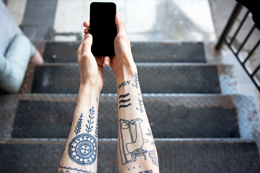 Tattooed man hands using a smartphone