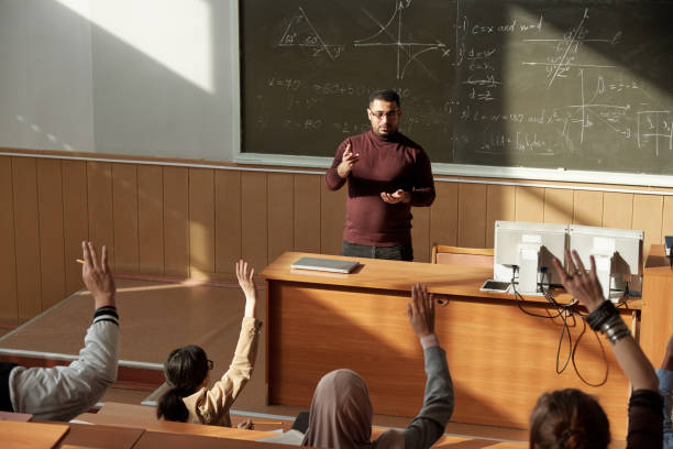 lehrer im mittleren alter in casualwear, die an der tafel im hörsaal stehen und schüler anschauen - professor stock-fotos und bilder