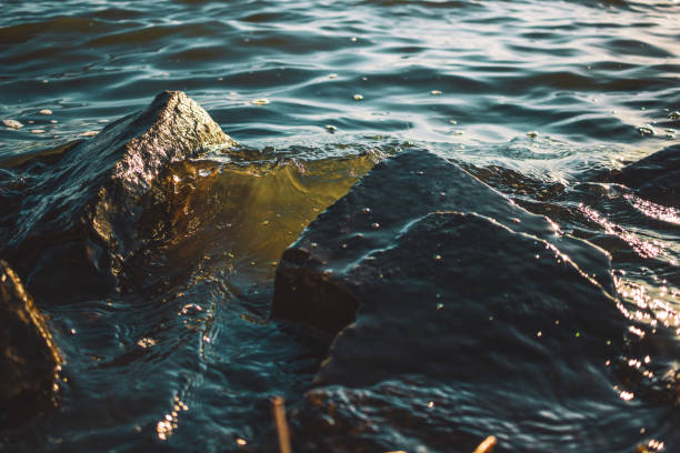water hitting stones by the lake shore at sunset