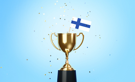 Star shaped gold confetti falling onto a gold cup in which a tiny Finnish flag sitting before blue background. Horizontal composition with copy space. Front view. Championship concept.