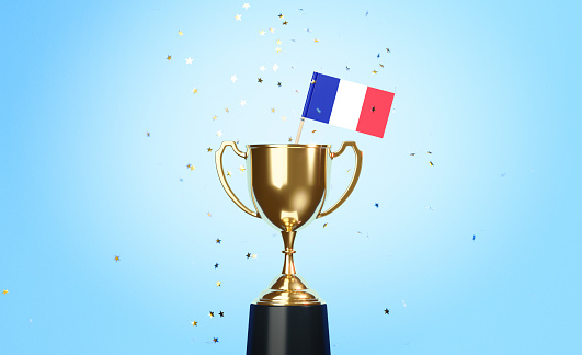 Star shaped gold confetti falling onto a gold cup in which a tiny French flag sitting before blue background. Horizontal composition with copy space. Front view. Championship concept.
