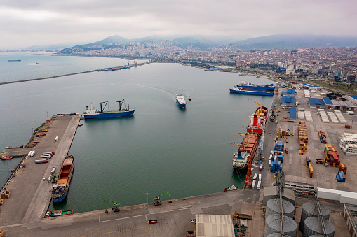 Aerial view of Ro-Ro ship carrying trucks. Cargo ship approaching to a commercial dock.