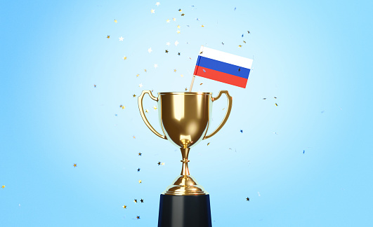 Star shaped gold confetti falling onto a gold cup in which a tiny Russian flag sitting before blue background. Horizontal composition with copy space. Front view. Championship concept.