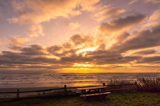 A picnic table overlooking the Pacific Ocean under a beautiful colorful sunset on the Washington coast